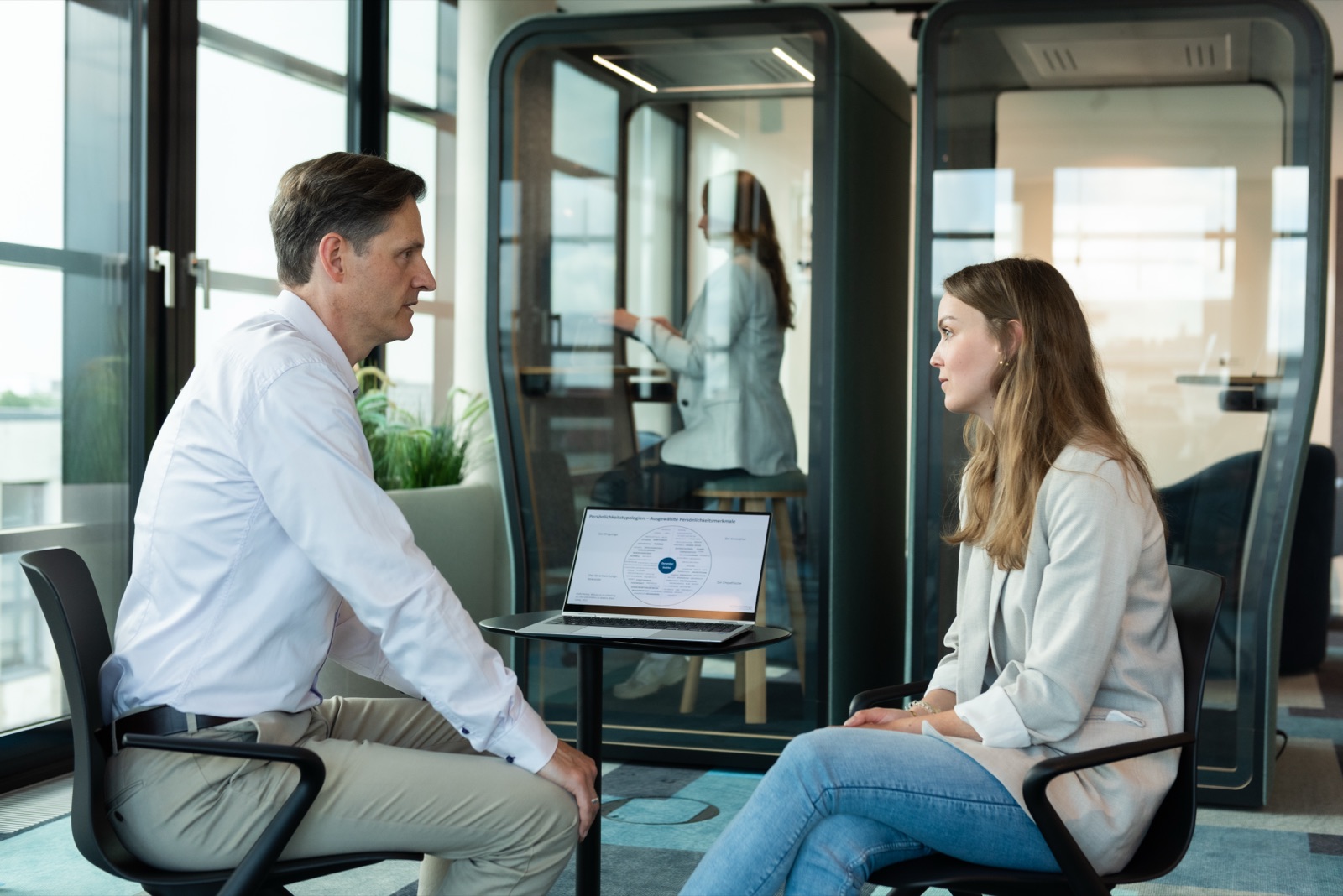 Beratungsgespräch zu zweit vor dem Meeting-Booth, auf dem Laptop das Gesamtbild Führung
